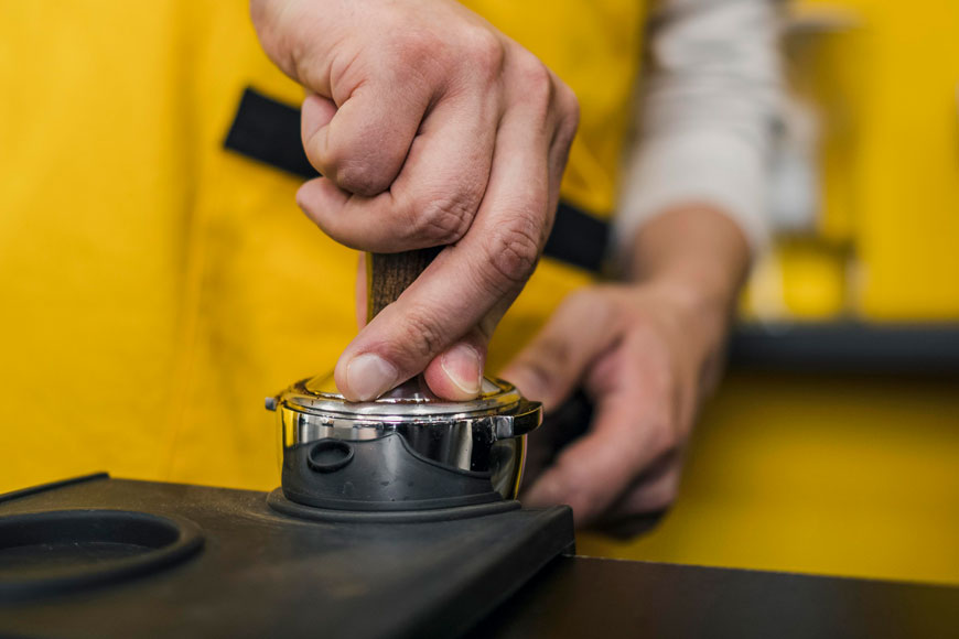 low-angle-male-barista-packing-coffee-machine